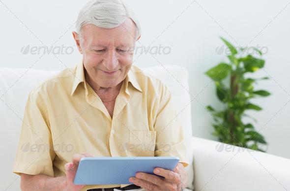 Elderly man using a digital tablet on a sofa (Misc) Photo Download