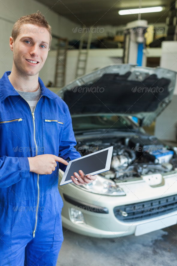 Portrait of happy mechanic using tablet computer with car in background (Misc) Photo Download