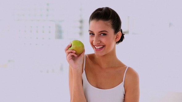 Amused Beautiful Woman Smelling And Showing Apple Amused Beautiful Woman Smelling And Showing Apple