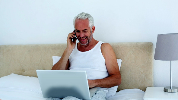 Laughing Man Using Laptop While On The Phone Laughing Man Using Laptop While On The Phone