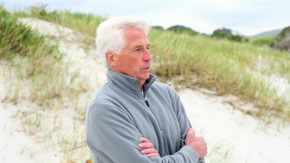 Retired Man Standing On The Beach Shivering Retired Man Standing On The Beach Shivering