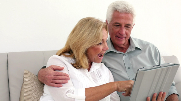 Retired Happy Couple Using Their Tablet Retired Happy Couple Using Their Tablet