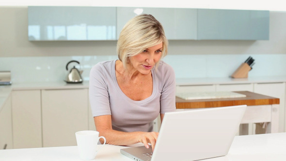 Blonde Woman Drinking Coffee Using Her Laptop Blonde Woman Drinking Coffee Using Her Laptop